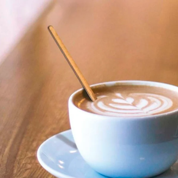 Removedor, Mezclador, Revolvedor o Agitador de café descartable de papel biodegradable dentro de una taza blanca de café con leche. Solución ecológica para hostelería.