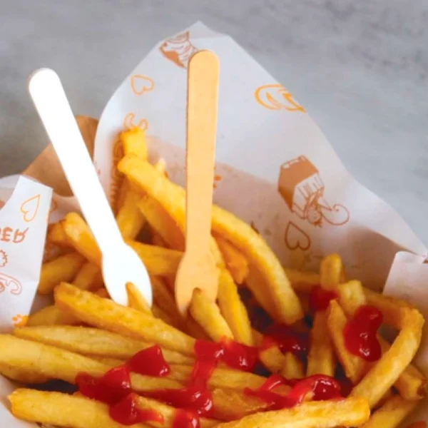 Picks de papel compostable con patatas fritas y kétchup, servido con cubiertos de papel biodegradables. Opción sostenible.