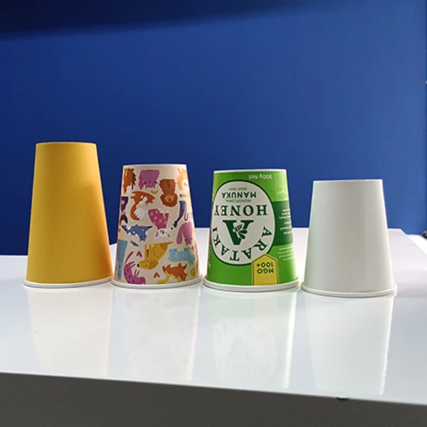 Cuatro vasos de papel biodegradables y compostables en colores y diseños variados (amarillo, animales, verde, blanco). Solución ecológica para bebidas.